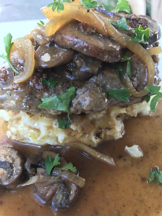 Serious comfort food here! Salisbury steaks packed with flavor, in mushroom and onion gravy and served here over some serious smashed potatoes.