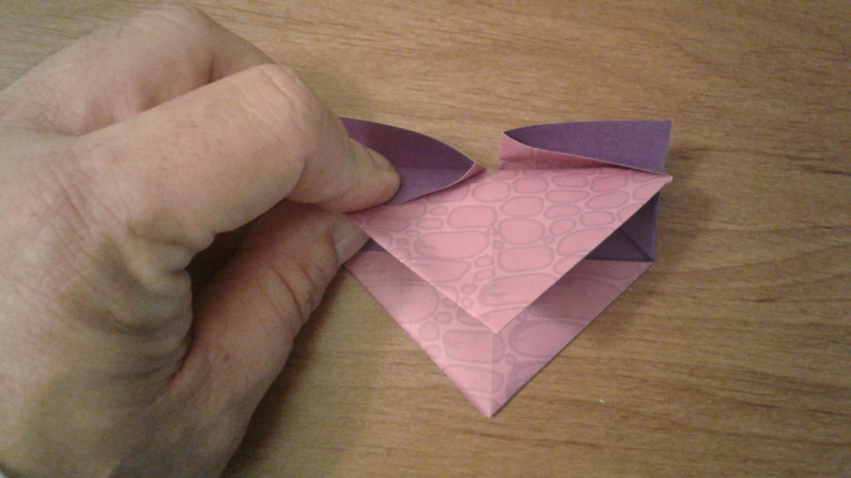 grab the top and fold it down towards the bottom triangle but don't crease it