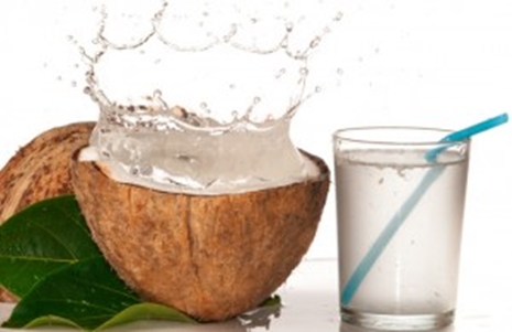 A Coconut with coconut water splashing and a glass of coconut water. 