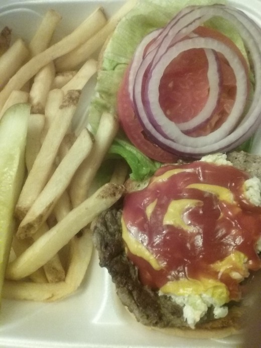 Generous condiments and lettuce, tomato and red onion on a burger with fries from Oakcrest Family Restaurant.