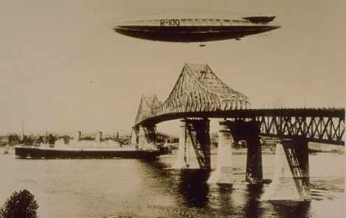R-100 passing over the Jacques Cartier Bridge / Pont Jacques-Cartier in Montreal, 1930 Collection Michel-Bazinet