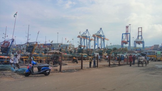 The harbor area where fishing boats are docked. Cargo containers which are stacked in the seaport area can be seen in the background.
