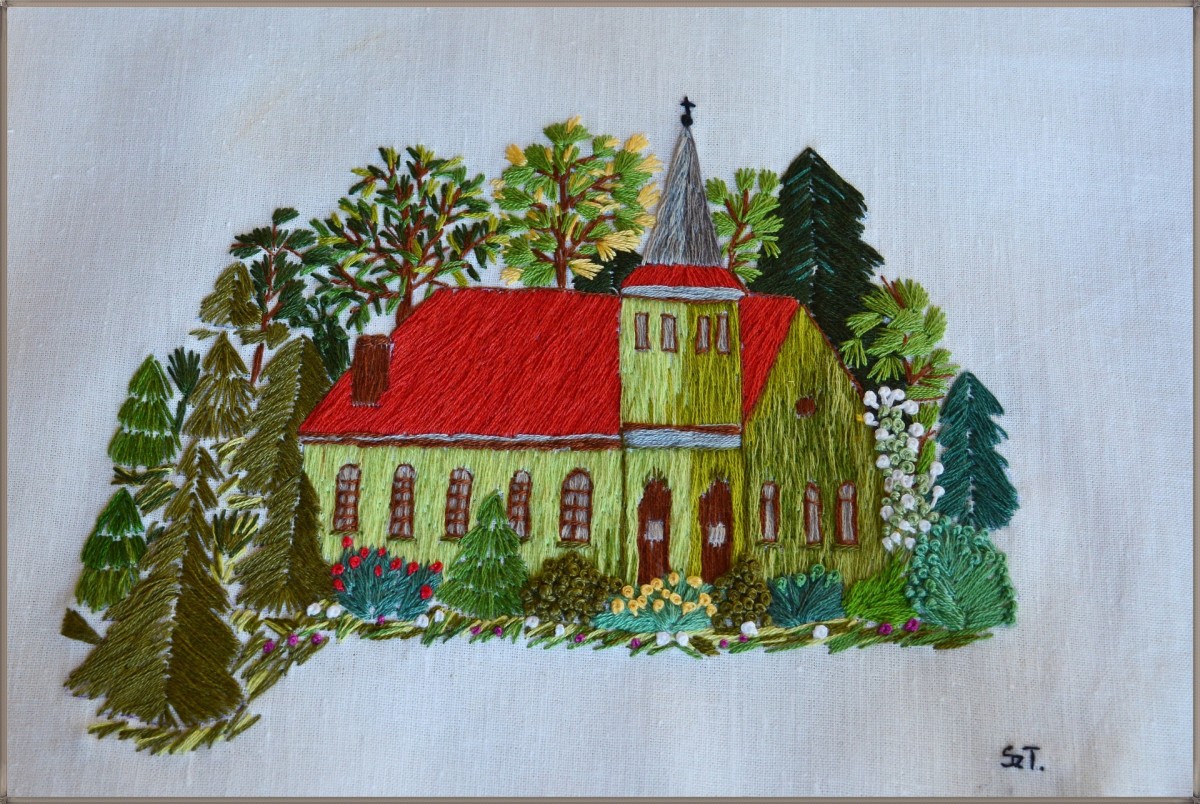 A hobby project of a green house with a red roof. The backyard is lined with tall trees. This hand labor makes a beautiful wall hanging. . 