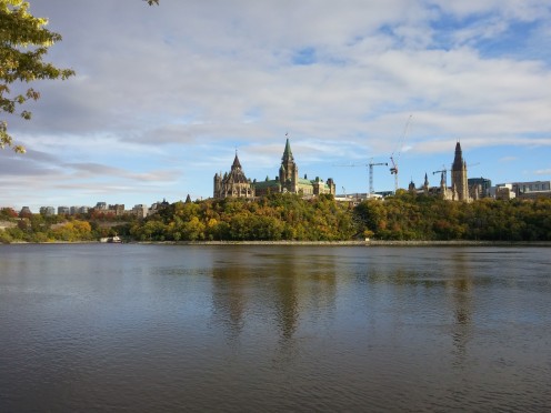 A photo of Parliament Hill in Ottawa, taken from the Sentier des Voyageurs / Voyageurs Pathway