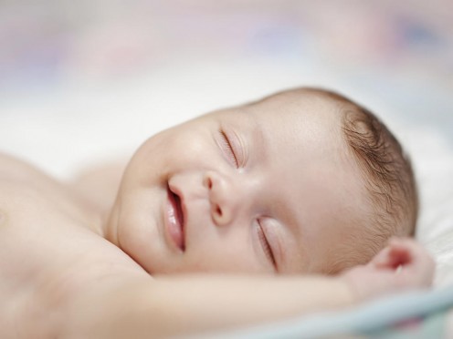 Cute baby appears to be smiling while sleeping.