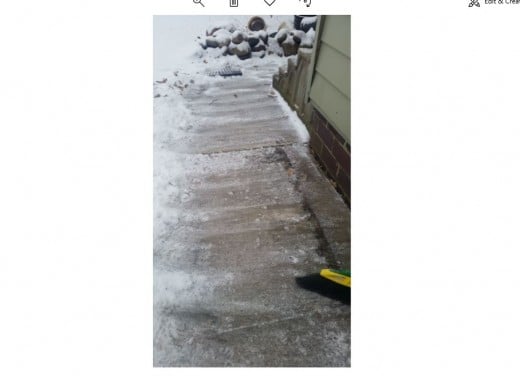 Sidewalk to door of house after sweeping snow debris from it