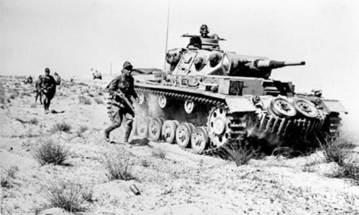 A German MKIII tank advancing along with infantry in North Africa.