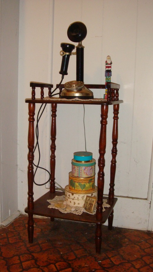 This is an old fashion phone stand. The phone on it is the kind you held separatly to hear/talk. On the phone book shelf I have a stack of round boxes! (I love boxes too!):)