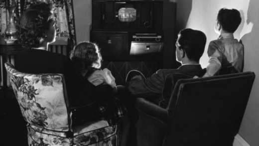 A family gathers around the living room TV, the chief threat to Hollywood over the last seventy years
