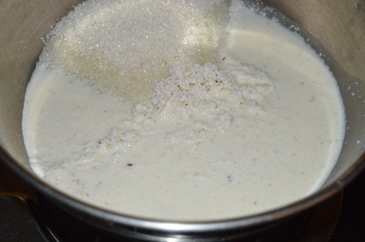 Step two: In a deep bottomed pan, add sugar, milk, and grated coconut. Heat the pan.