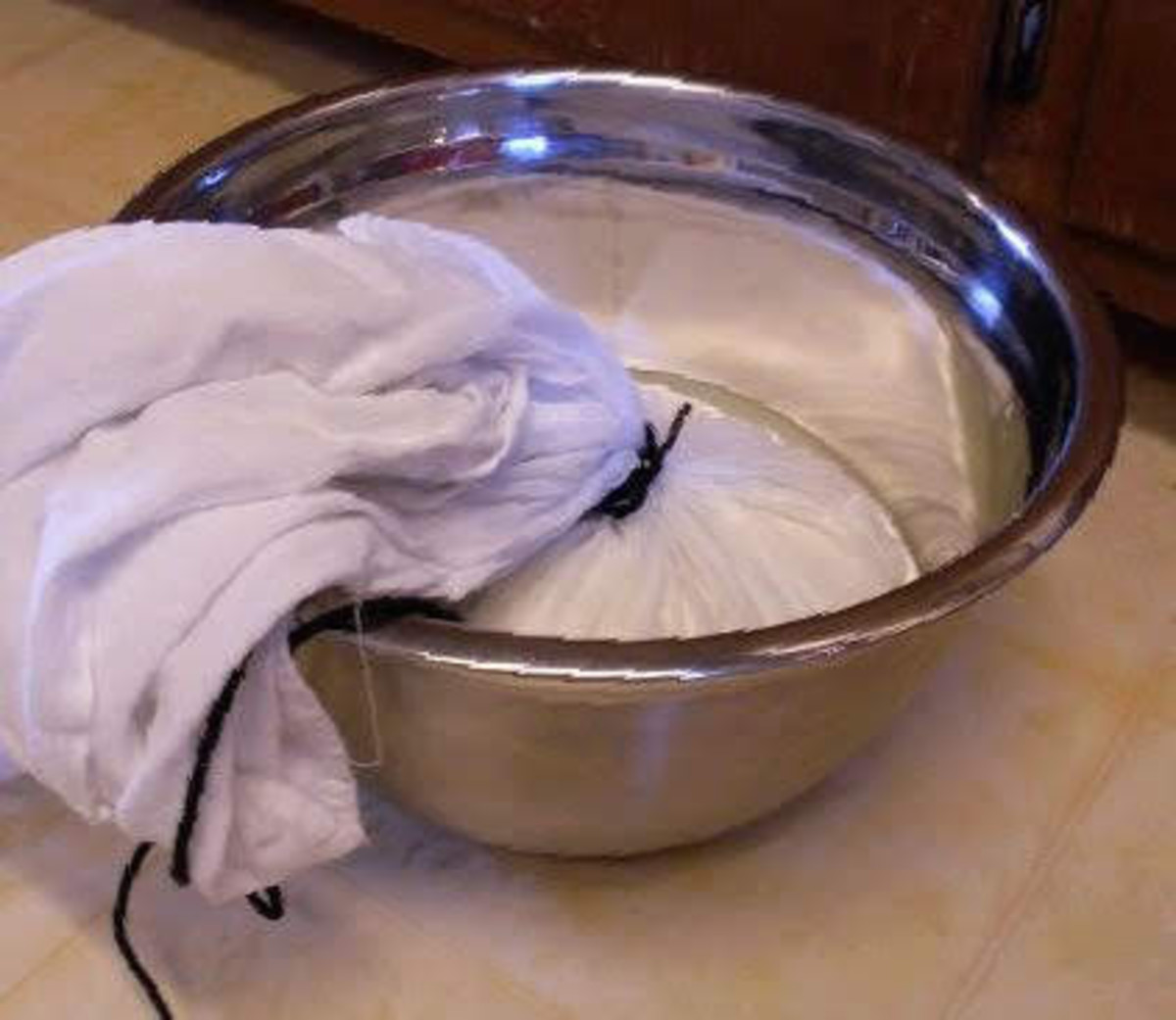 If you have more than one towel full of curds, as each releases most of its whey, tie it up and place it in a waiting bowl so you can get the next one draining.