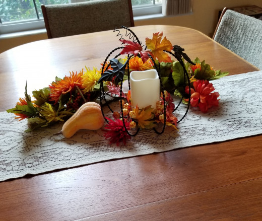 The runner is lace, the pumpkin is merely a metal outline leaving space for a candle, some leaves, and silk mums in autumn colors. 