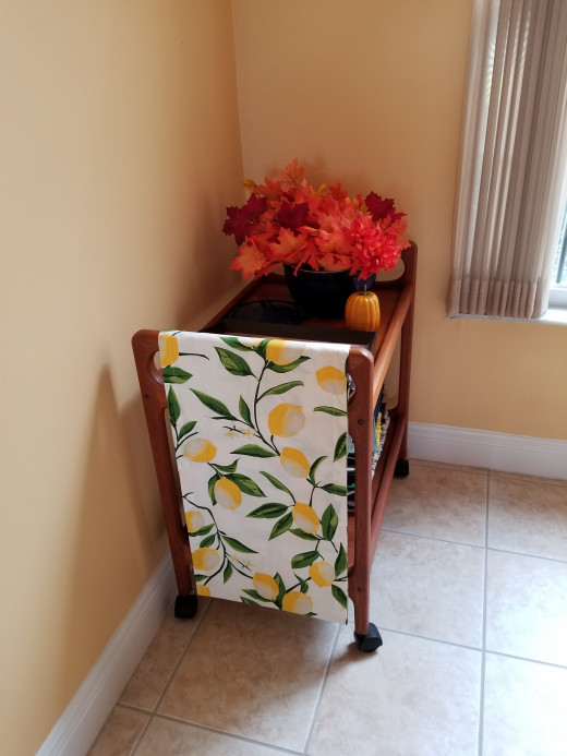 I arranged colorful leaves in a vintage navy bowl from the 1920s. The table runner of yellow lemons draws the eye to the serving cart and the arrangement.