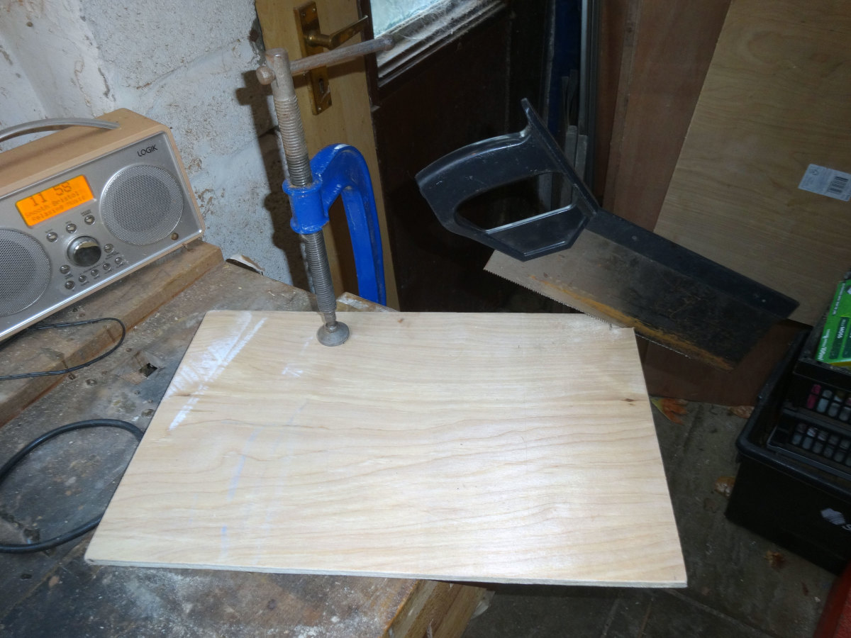 Plywood clamped to workbench to cut the notch with a handsaw