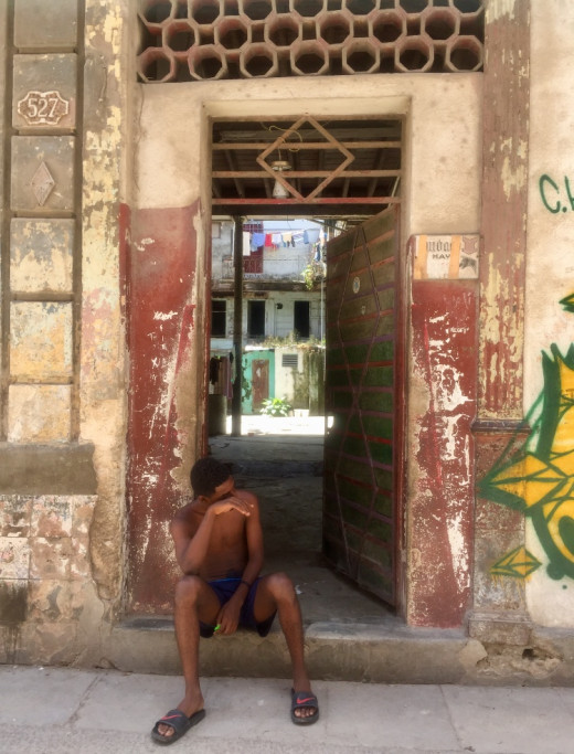 Young boy sitting on the doorstep in front of his home. What will the future bring?