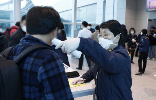 A female staff member places a device for taking a temperature quickly.South Korea professionals rely on more stringent tools than mere temperature testing of individuals who enter their buildings and cities.