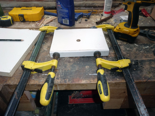 Gluing the uPVC trim to the front edge of the shelf, clamping it in place until the glue dries.