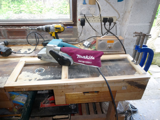 The panel frame is given a quick sanding with a belt sander.