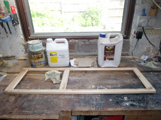The sandpaper, white spirit, teak oil, light oak coloured floor varnish, and light wood coloured beeswax laid out and ready for finishing the front panel frame.