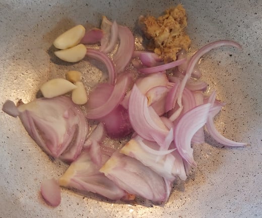 In a frying pan or vessel heat 1-2 teaspoons of oil. Add sliced onions, cloves of garlic and crushed ginger. 