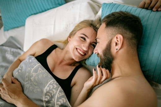 A man and a woman cozying up to each other in bed.