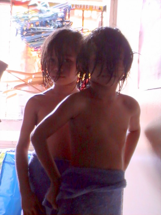 The twins share one towel after taking a bath.