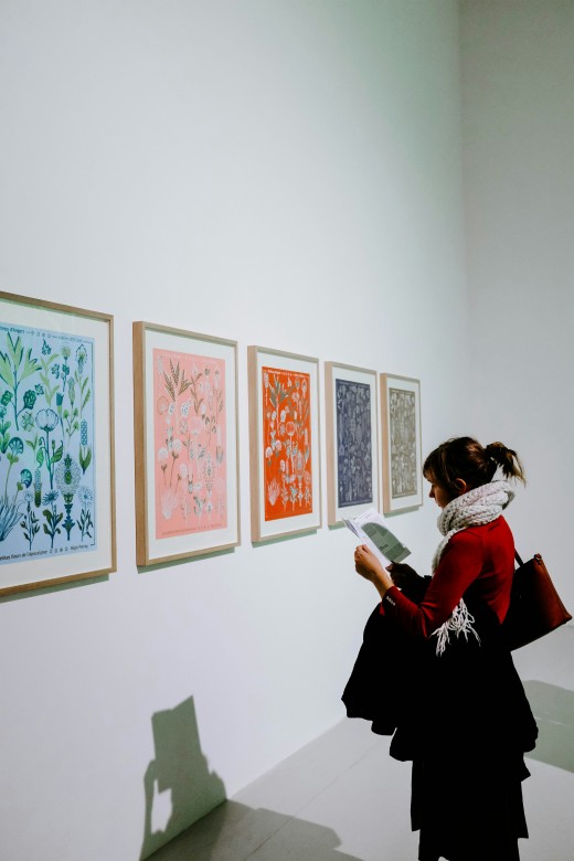Woman standing in front of paintings, photo by Adrien Olichon on Unsplash