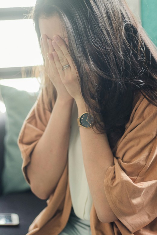 Woman in brown shirt covering her face, photo by Fa Barboza on Unsplash