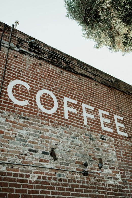 A brick wall with a sign that says coffee on it, photo by Adrian Ordonez on Unsplash