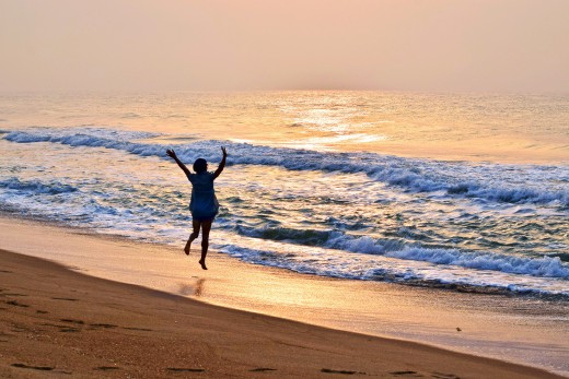 A person running on the beach with their arms in the air, photo by Omoniyi David on Unsplash