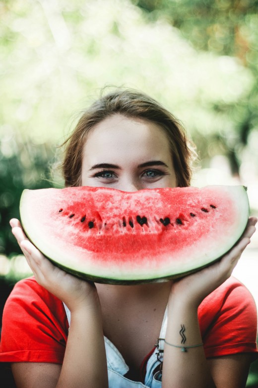 Woman holding sliced watermelon, photo by Caju Gomes on Unsplash
