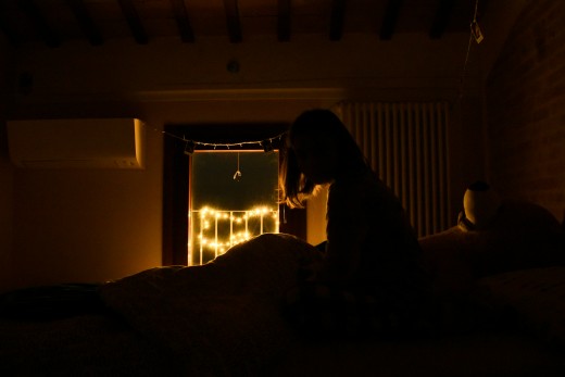 A person sitting on a bed in a dark room, photo by Greta Bartolini on Unsplash