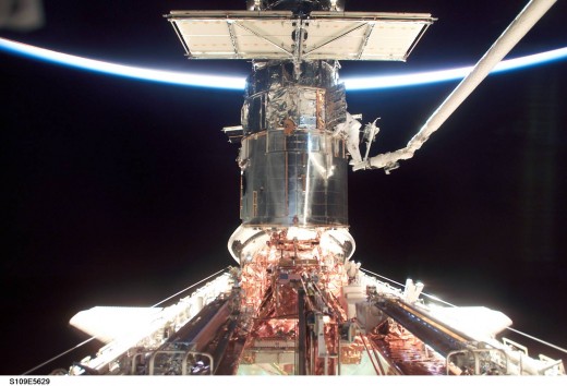 NASA astronaut on shuttle arm working on the Hubble telescope.