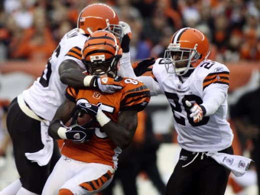 Chad Ochocinco, center, is tackled by Cleveland Browns defenders Abram Elam, left, and Mike Adams during the second half of their NFL football game in Cincinnati, Sunday, Nov. 29, 2009. (AP Photo/Tony Tribble)