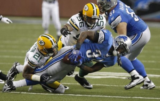Detroit Lions running back #34 Kevin Smith is pulled down by Green Bay Packers cornerback #21 Charles Woodson and linebacker #56 Nick Barnett (56) (AP Photo/Carlos Osorio)