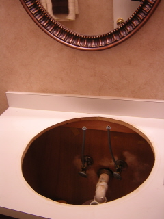 Sink removed from vanity to facilitate attaching faucet