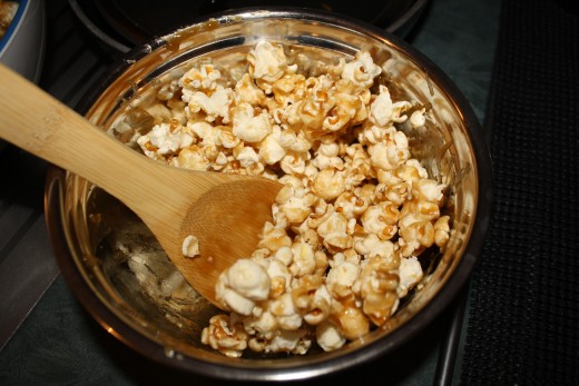 Coating the popcorn with caramel sauce.