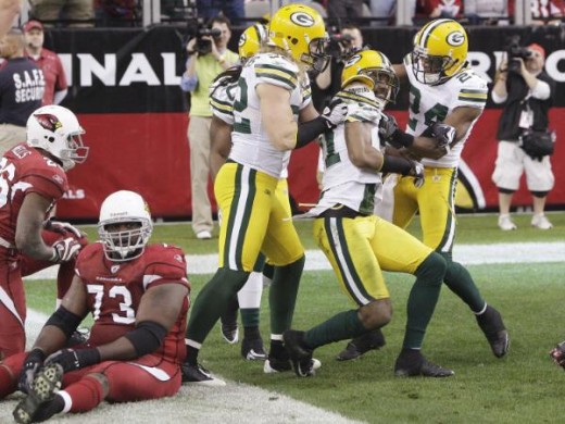 Green Bay Packers' Charles Woodson, second from right, celebrates his interception return for a touchdown with teammates Jarrett Bush (24) and Clay Matthews, front left, and Atari Bigby, back, as Arizona Cardinals' Jeremy Bridges (73) sits on the gro