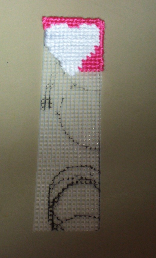 Here I began stitching on the pink yarn that will surround the adorable white yarn heart.