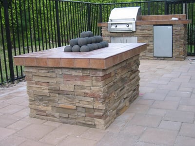 Gas fire pit with cannonballs built to match a small grill island.