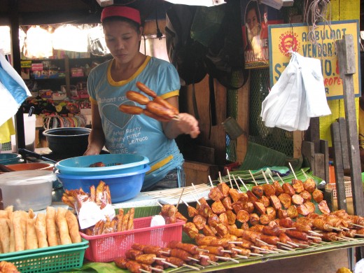 A vendor selling fried banana-que, camote-que as in BBQ also in the lower left there is Turon - bananas wrapped in lumpia wrapper then fried.