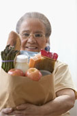 Portrait of a senior woman holding fruits and vegetables in a paper bag