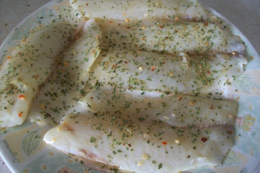 Uncooked tilapia, seasoned after marinating them.