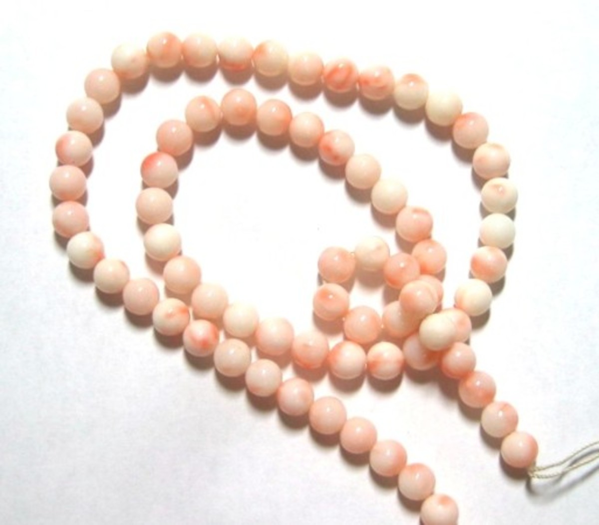 Pink and white coral bead. These are also angel skin coral, but the color is darker and a little more splotchy than the ones on the left. This coral is all natural and has not been dyed.
