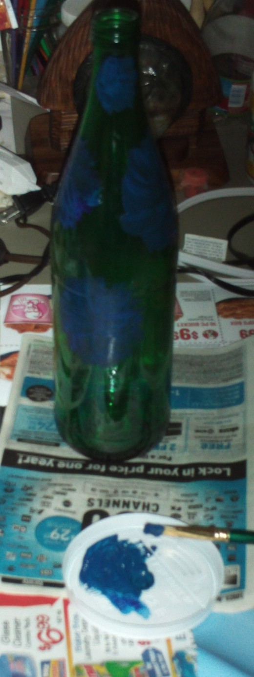 In this step I begin to paint on the azure flowers.  For this project I have recycled many items such as the glass bottle I am turning into a vase, and the disposable cup lid I am using for a paint palette.