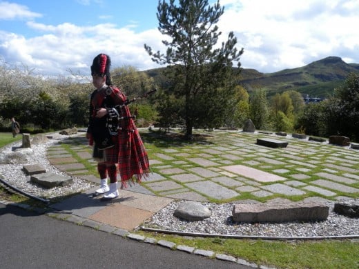 A beautifully dressed Scottish bag pipe player was playing inside the stone circle.  Each stone is a specific type of stone taken from each Scottish shire.
