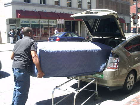 Eric Lusain, Owner of Main Street Casket Company, loads a casket into the back of his Prius for delivery. After a brief interview in his showroom, Mom snapped pictures and Son recorded a video of Eric pushing the casket down the sidewalk and loading 