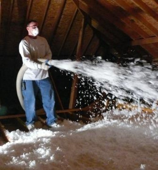 A man spraying in insulation into an attic-make sure he doesn't get any in your emergency drain pan!