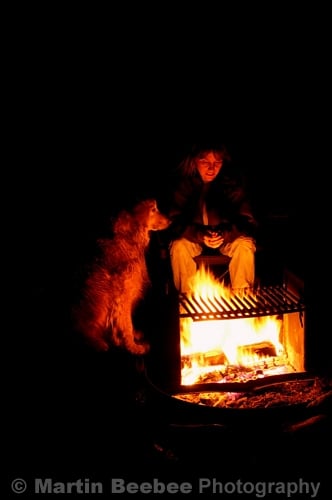 Fireside Golden Retreiver sits loyally with his human friend.