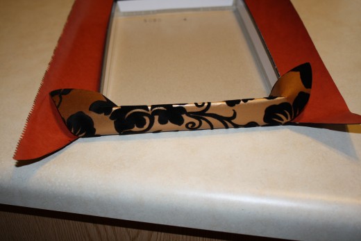 Step five: start at the short sides of the lid, fold in the paper and tape using 2 inch strips of tape. 